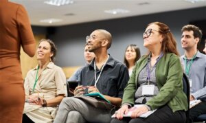 A group of six professionals sitting in rows, looking at a person presenting who is partially out of shot
